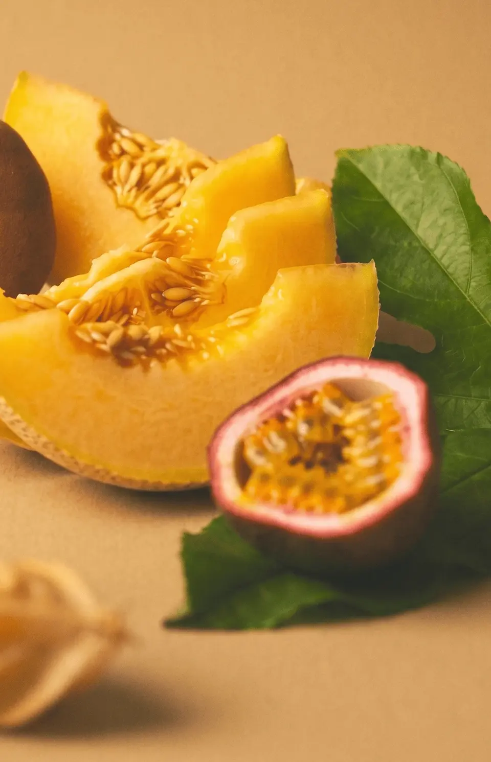 Close-up of melon, passion fruit, and green leaves used as natural ingredient-inspired styling for the Solenne skincare and haircare brand world.