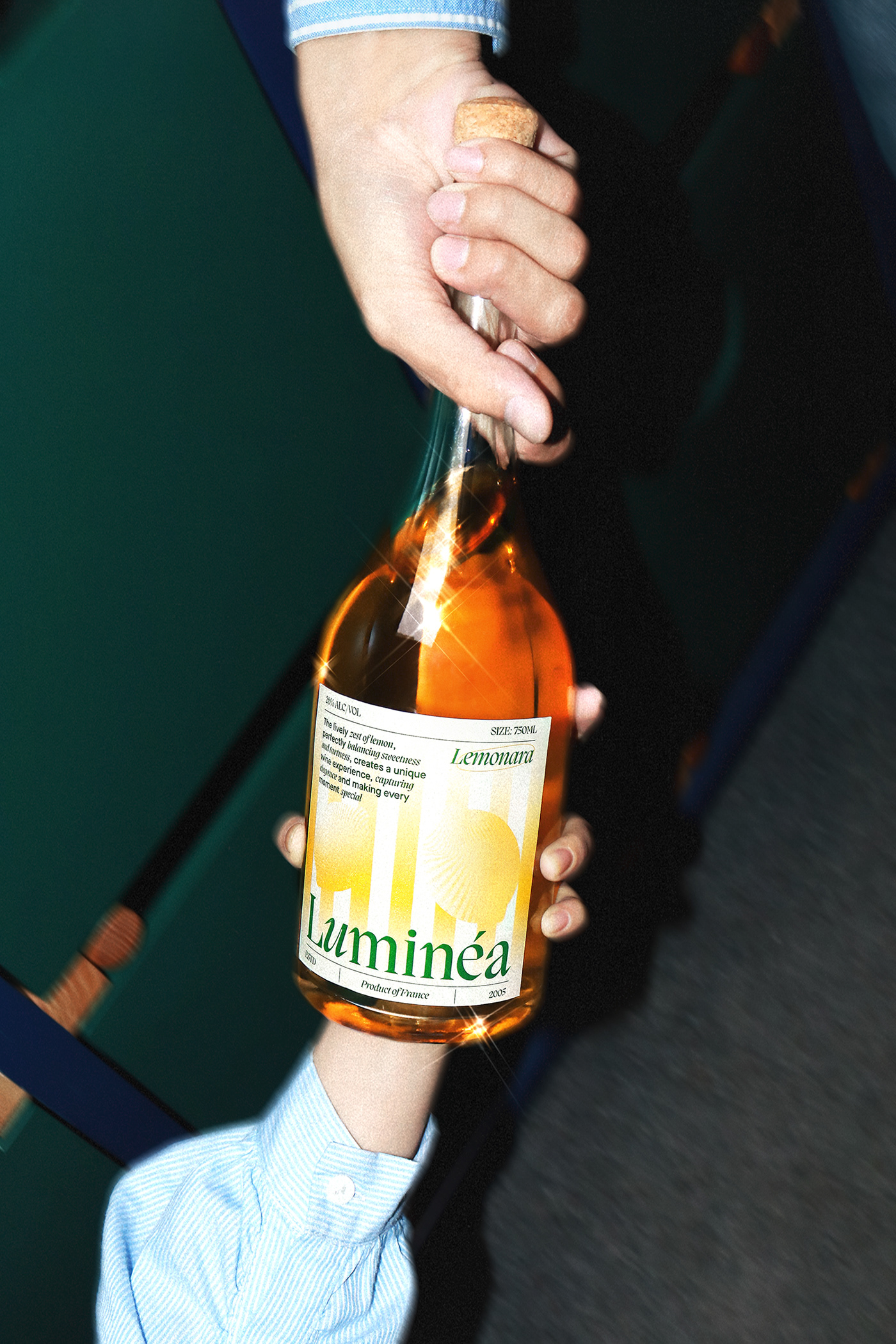 Hand holding a Luminéa Lemonana wine bottle against a dark green backdrop, highlighting the yellow gradient label design and modern editorial typography.