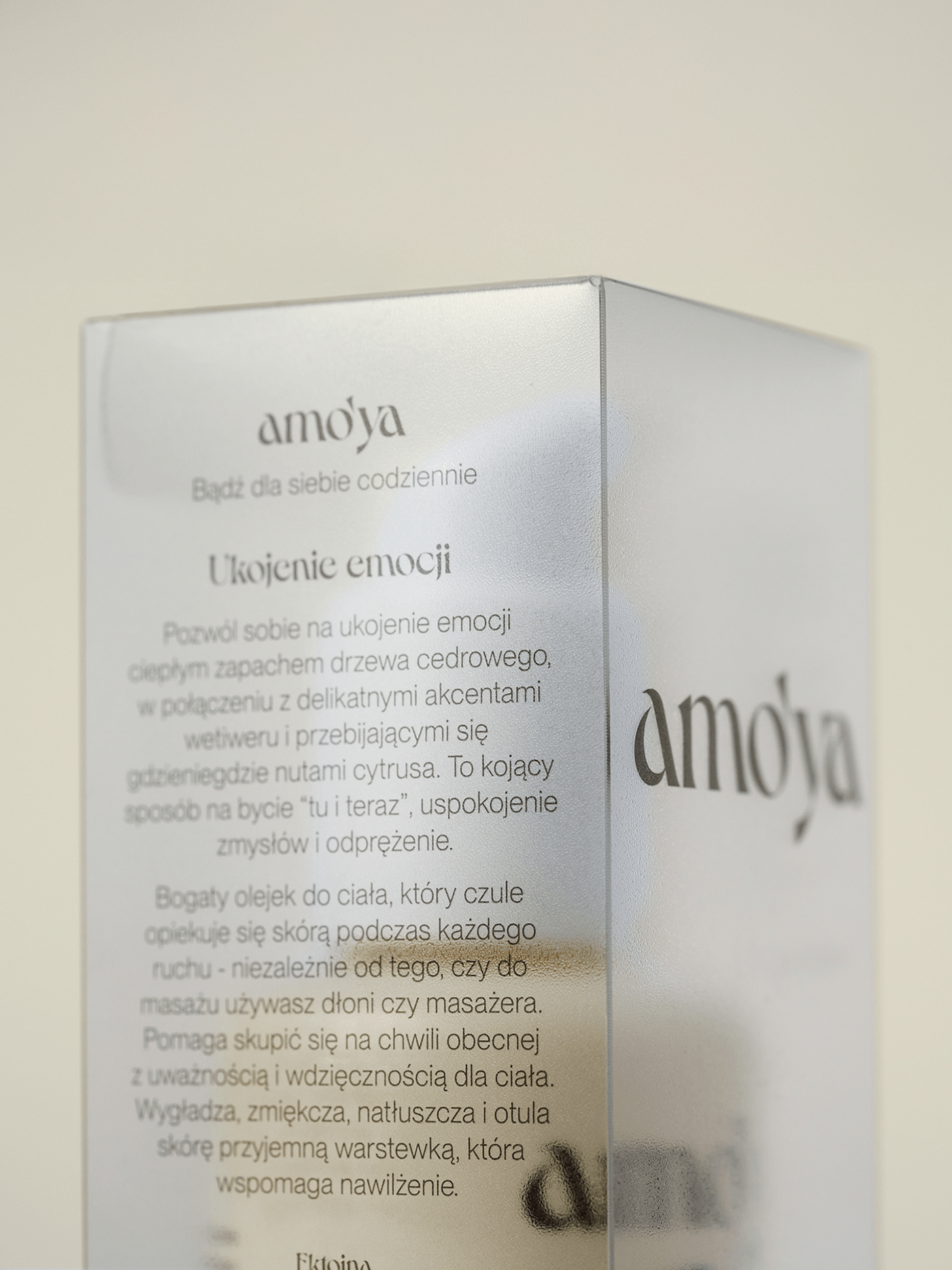 Close-up of Amo’ya translucent frosted packaging, showing layered Polish typography and the refined serif wordmark through the semi-transparent surface.