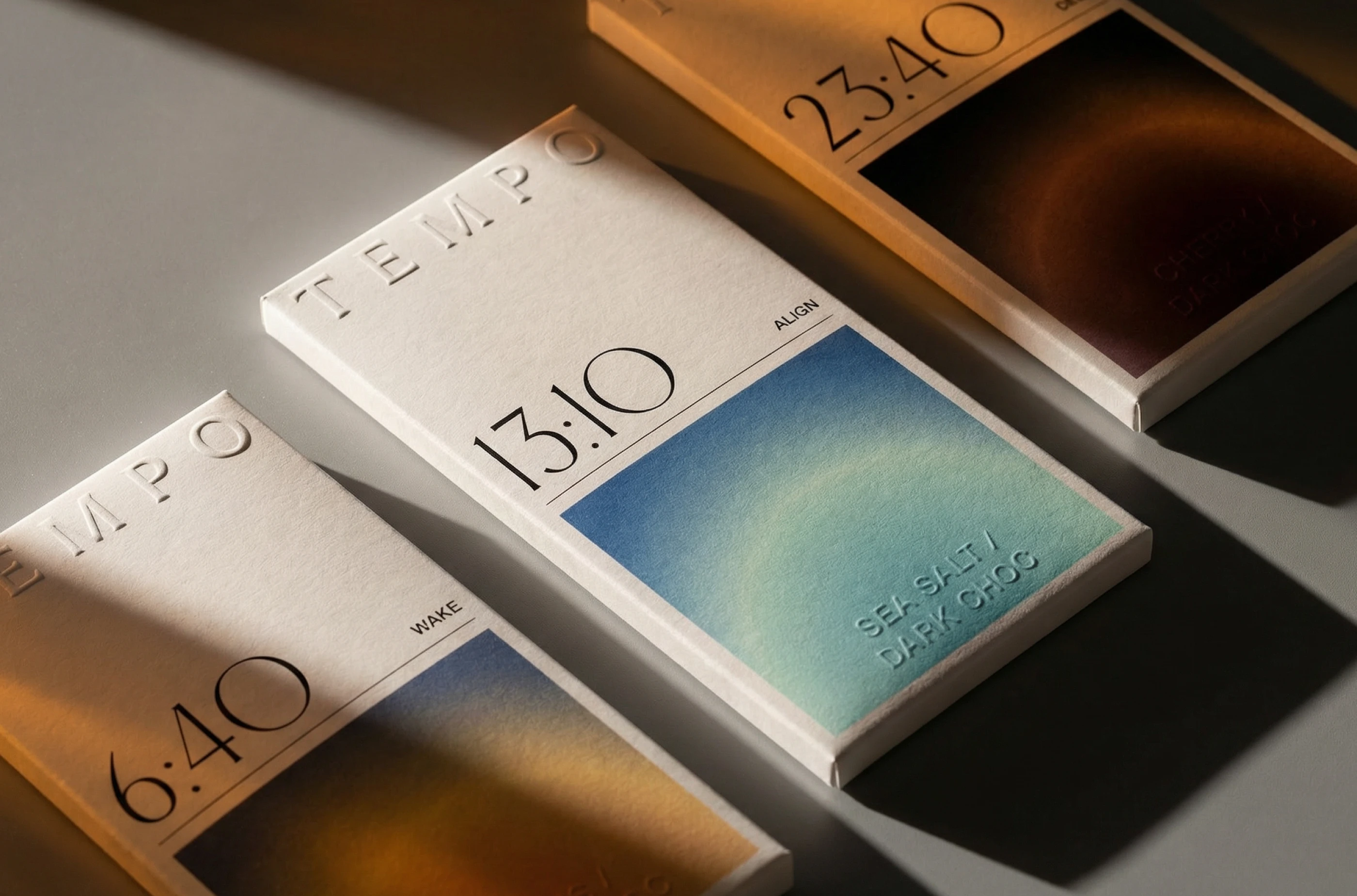 TEMPO chocolate packaging design by LYM Design Studio showing three time-based chocolate bar boxes with embossed branding, gradient flavor panels, warm lighting, and minimal premium packaging details.