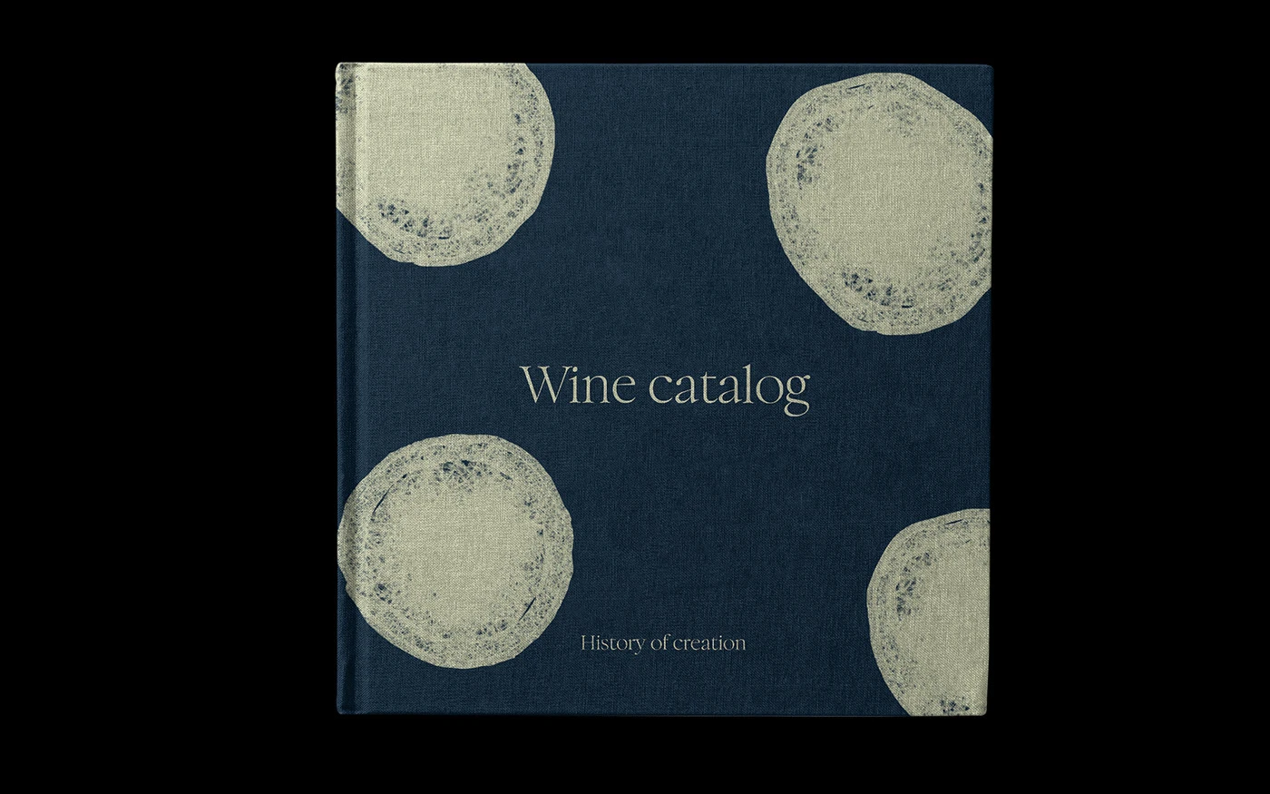 The cover of the 'Wine catalog | History of creation' book in deep slate blue fabric texture, featuring four large, abstract white grape cross-section patterns in the corners.