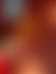 Hand holding a Negroni cocktail over a leather-textured surface decorated with colorful geometric coasters.