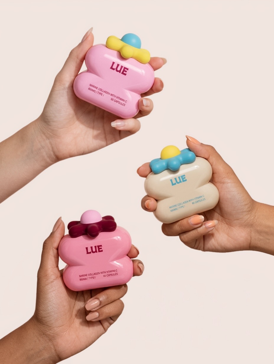 Three hands holding sculptural LUE collagen cosmetic vessels in pink and cream, featuring rounded capsule-like forms with colorful dimensional caps.