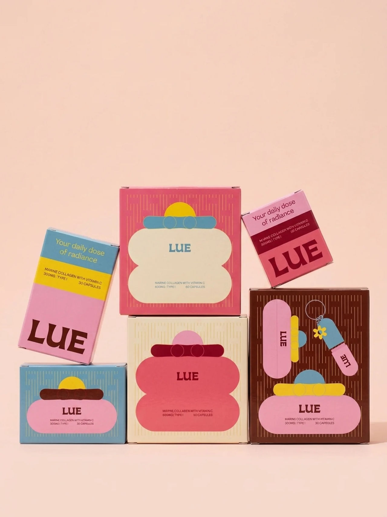 Stacked LUE cosmetic packaging boxes in pink, blue, cream, and brown with playful graphic shapes for a marine collagen and vitamin C product line by Studio Kopaz.