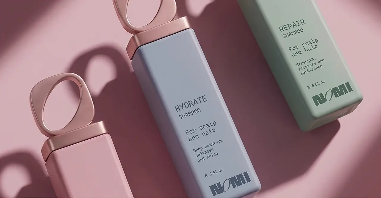 Pink, blue, and green NOMI shampoo bottles arranged diagonally with sculptural loop caps and strong shadows on a blush background.