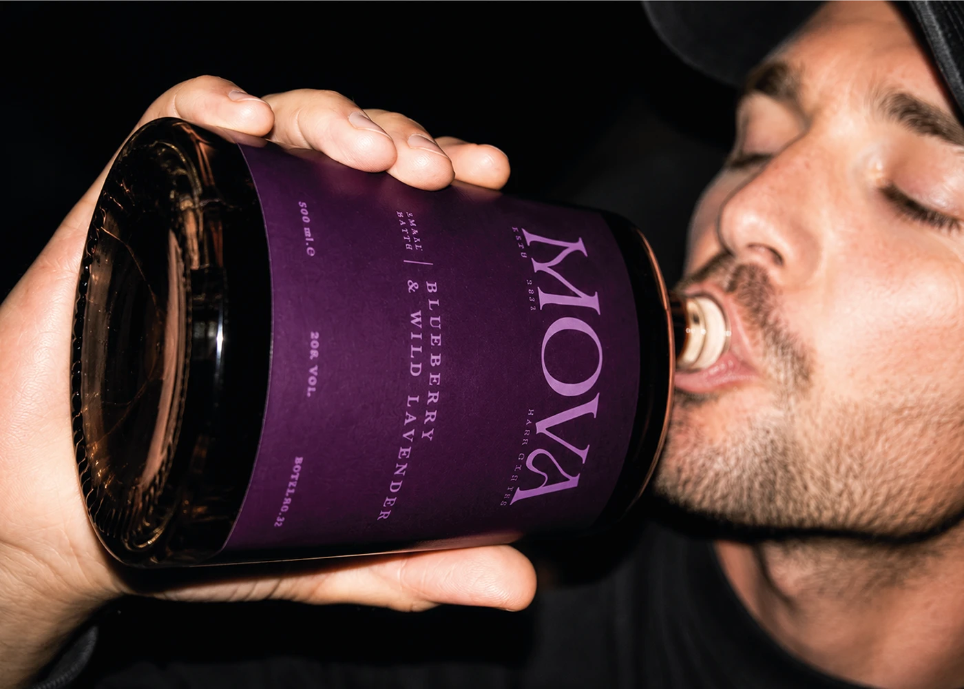 Close-up of a man drinking from a MOVA blueberry and wild lavender liqueur bottle.