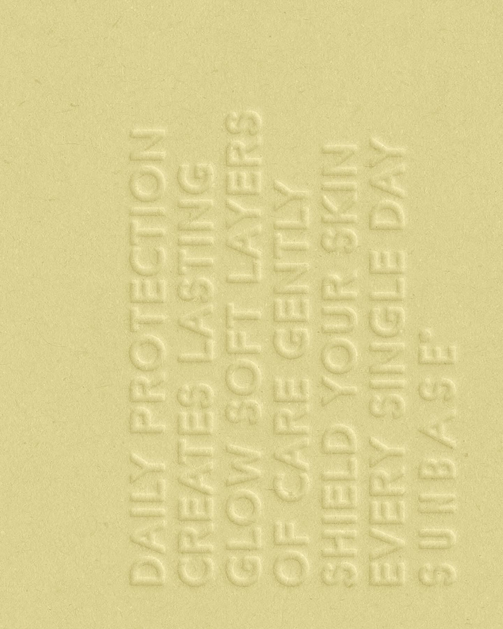 Embossed skincare text texture on soft yellow surface, tactile packaging detail for Sunbase brand identity