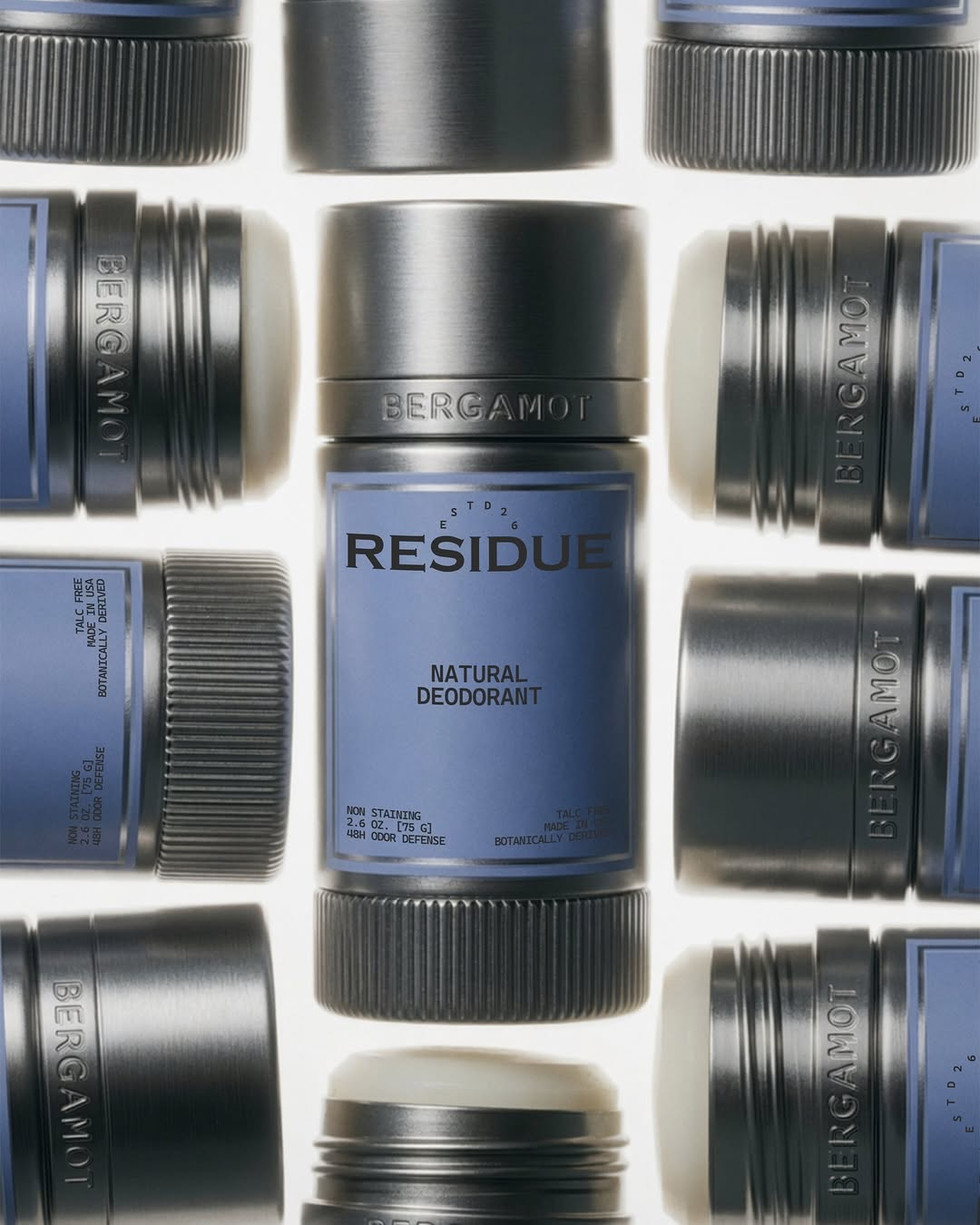 Multiple silver natural deodorant sticks arranged in a geometric flat lay, with powder blue labels, ribbed black bases, and engraved bergamot scent names.