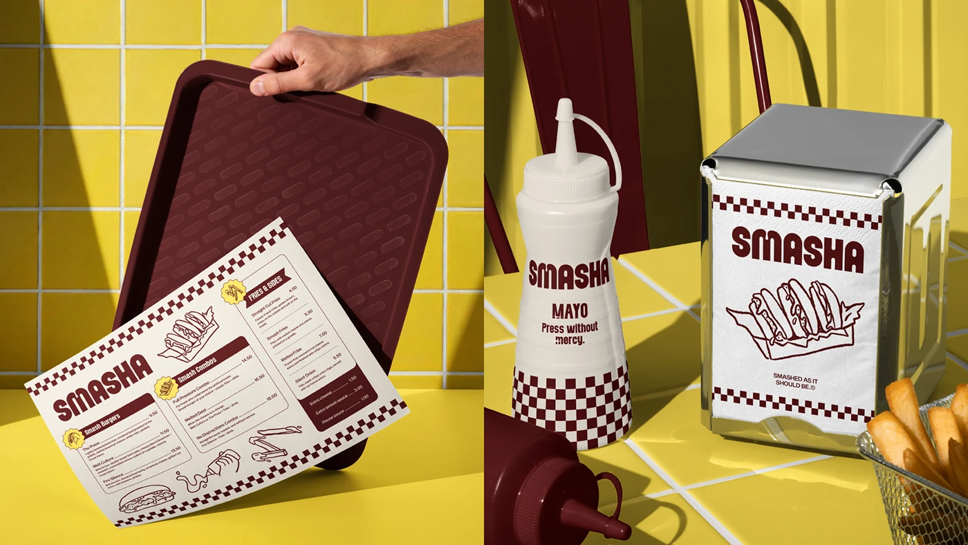 Smasha menu board resting on a tray beside branded squeeze bottles, napkin dispenser, and fries, styled against yellow tiled backdrop with checkerboard accents