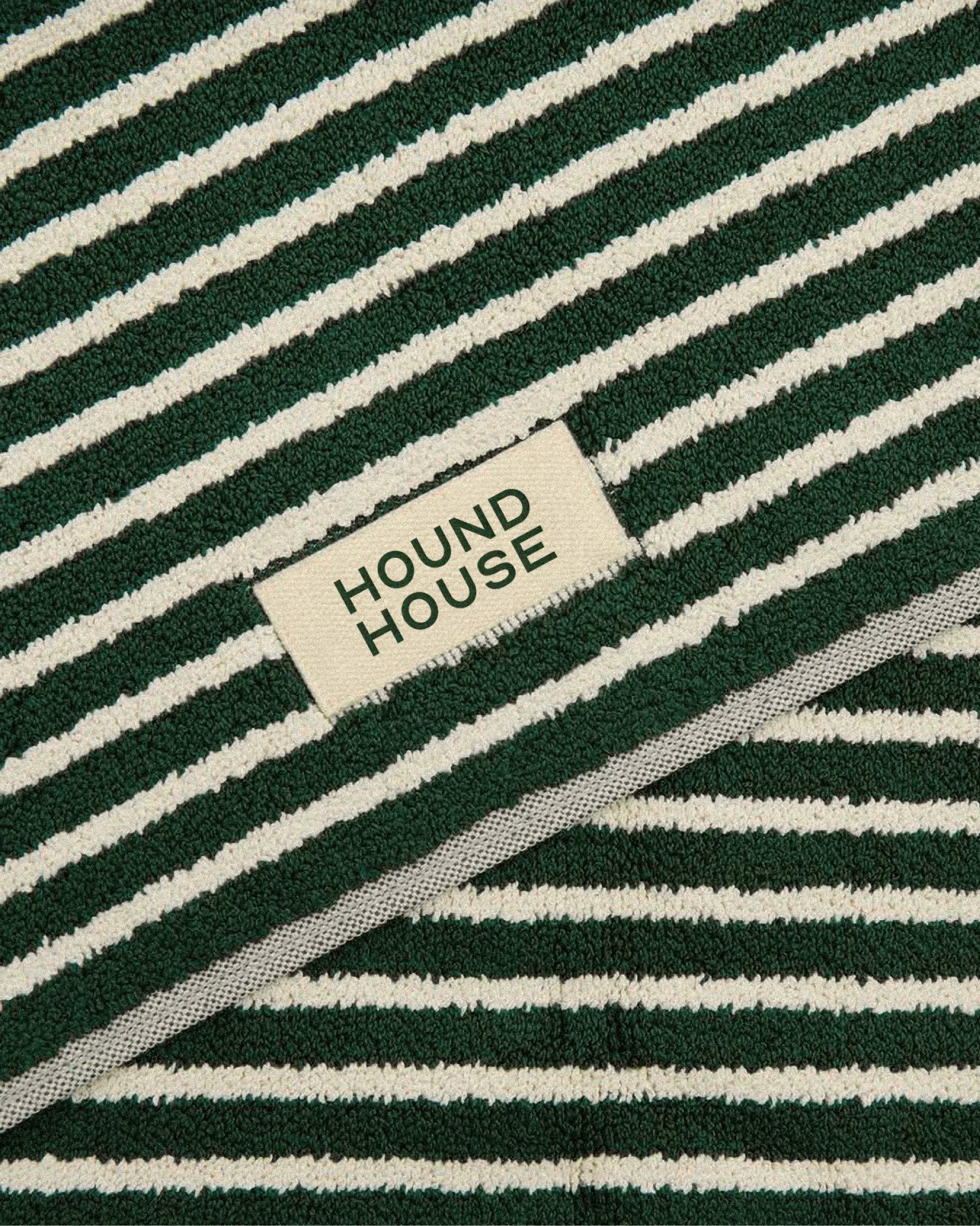Close-up of striped textile featuring a woven Hound House label, highlighting branded fabric and material applications within a pet hospitality brand identity.