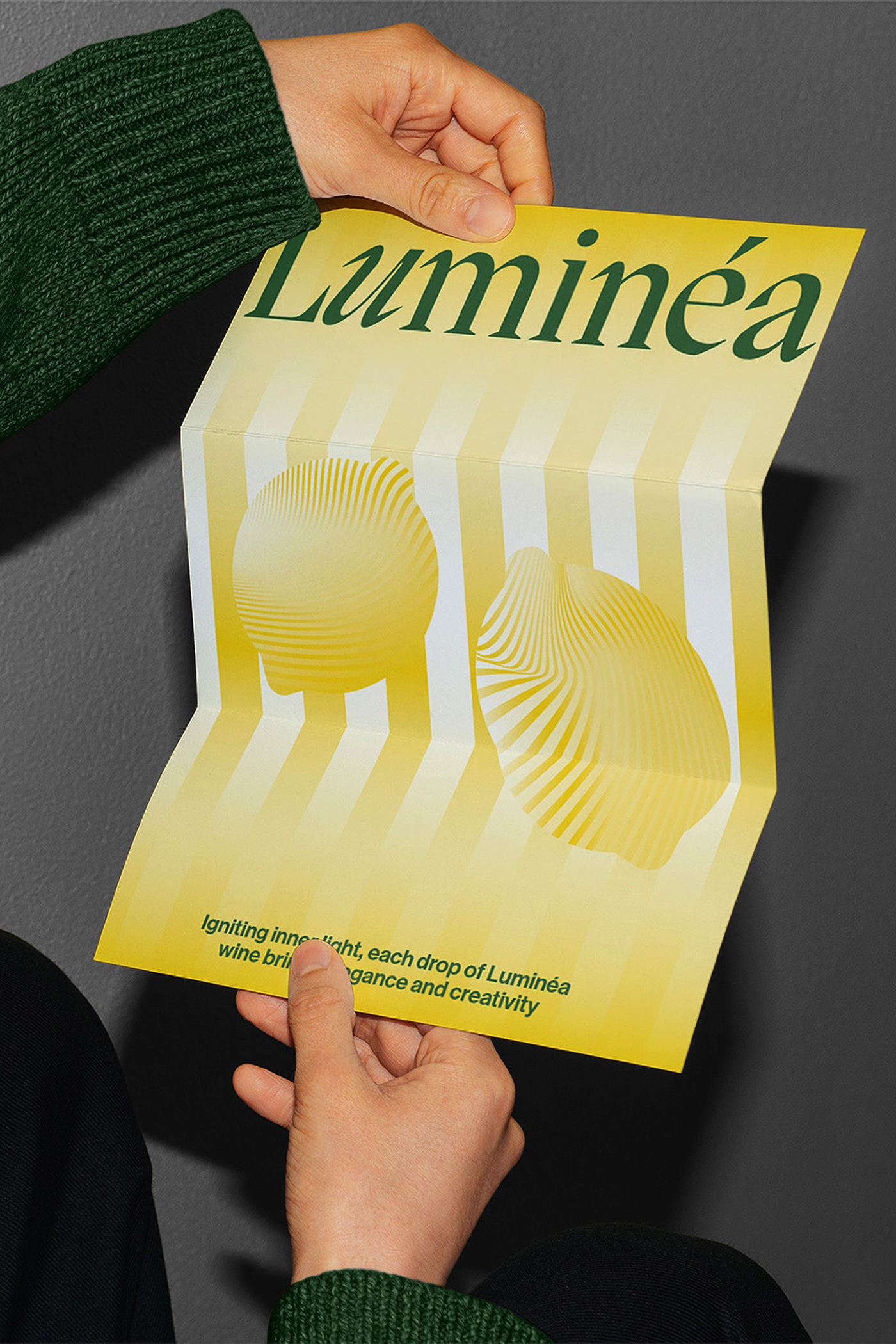 Hands unfolding a yellow Luminéa poster with gradient lemon-inspired graphics and serif typography, showcasing the brand’s modern packaging identity and expressive color architecture.