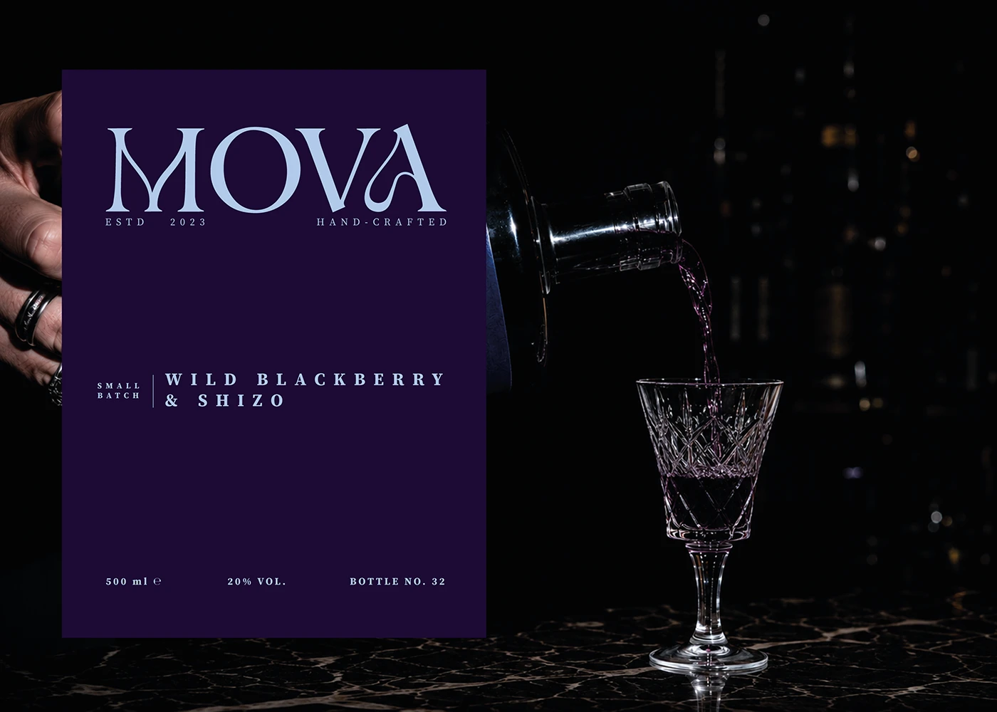 MOVA wild blackberry and shiso liqueur label beside a bottle pouring purple liqueur into a crystal glass.