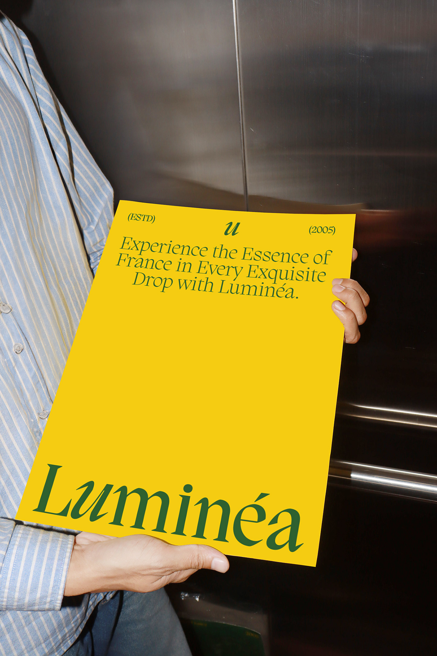 Person holding a large yellow Luminéa poster in an elevator, showcasing the brand’s modern serif typography and vibrant luxury-focused color palette.