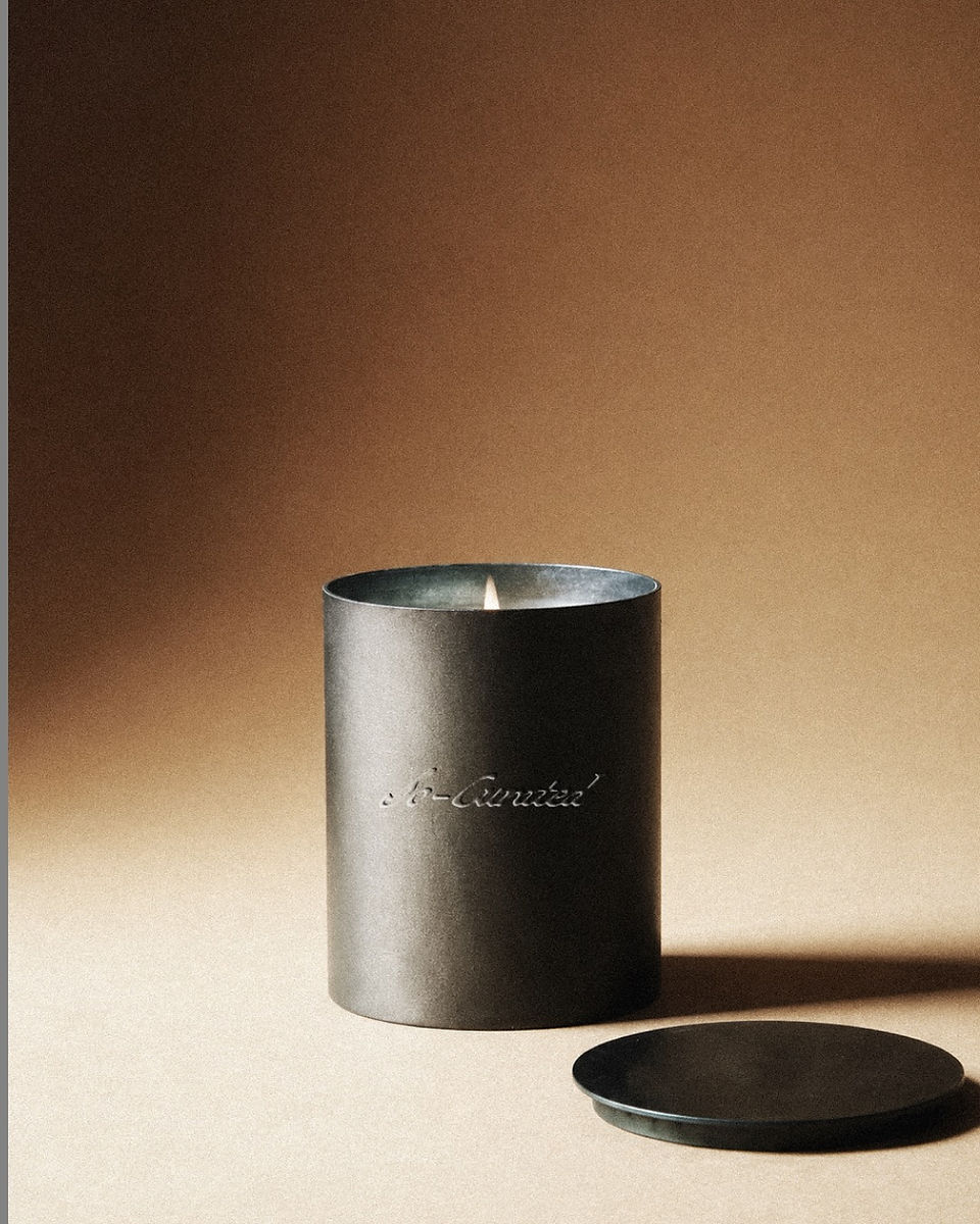 Minimal black candle for So Curated featuring an embossed script logo, photographed in warm directional light with a soft neutral backdrop.