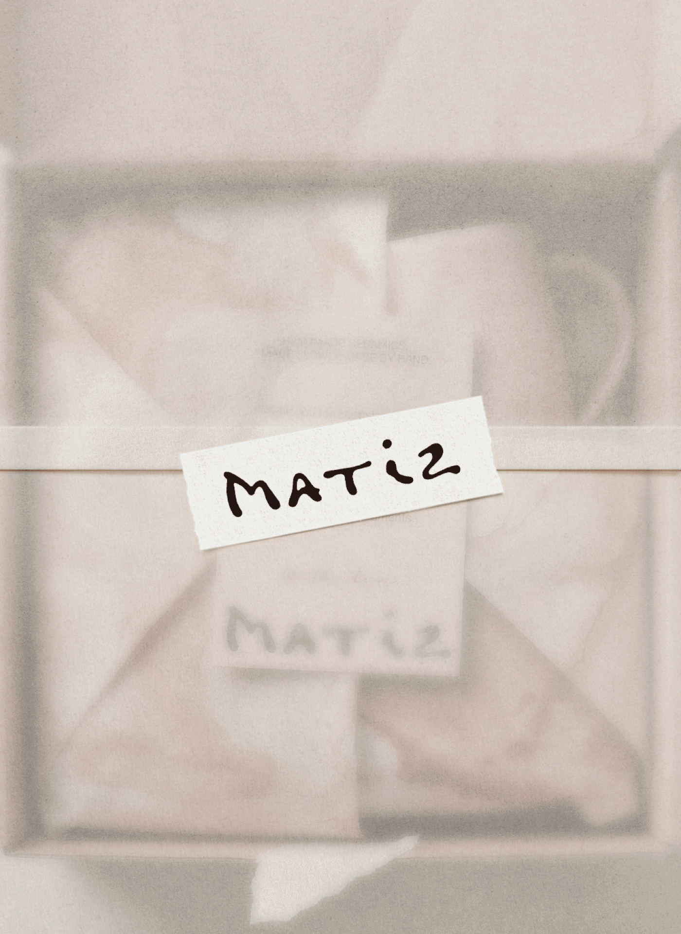 Translucent paper covering an open box with a ceramic mug and printed inserts, secured with a white MATIZ logo sticker.