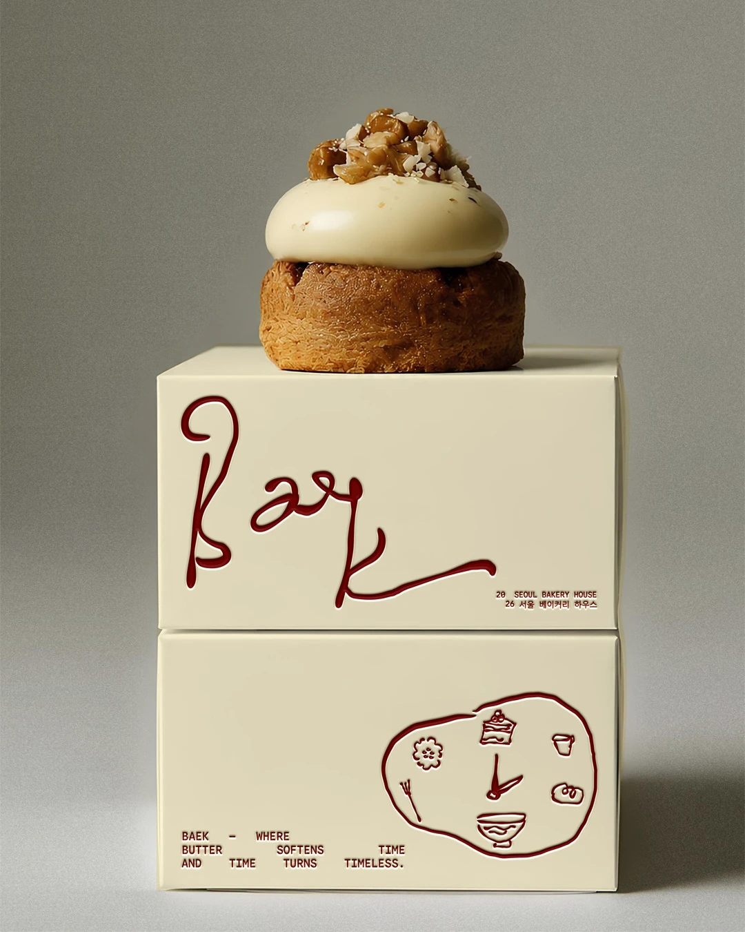 Baek Korean Bakery packaging mockup with two cream pastry boxes, deep red handwritten logo details, small illustrated bakery icons, and a pastry displayed on top.