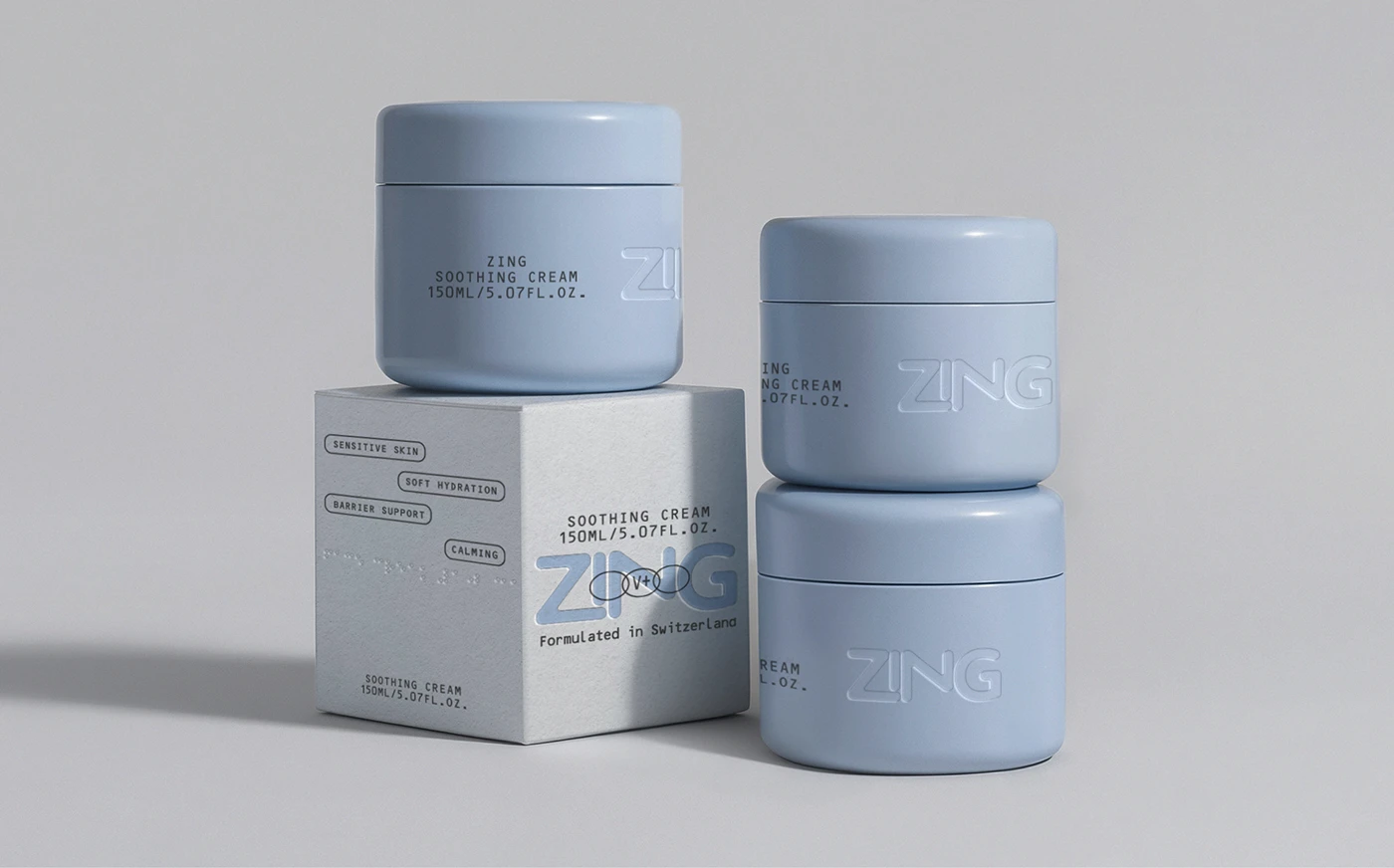 ZING soothing cream jars and carton packaging displayed in a clean studio setting, featuring soft blue containers, embossed logos, textured paper, and sensitive-skin messaging.