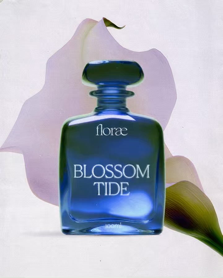 Florae Blossom Tide perfume bottle photographed with soft botanical elements, showcasing the sculptural glass form and refined fragrance typography.