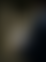 A man wearing a dark blue linen robe in a sophisticated art gallery, holding a JUDE candle box and a personalized note, showcasing luxury branding and the emotional resonance of gifting.