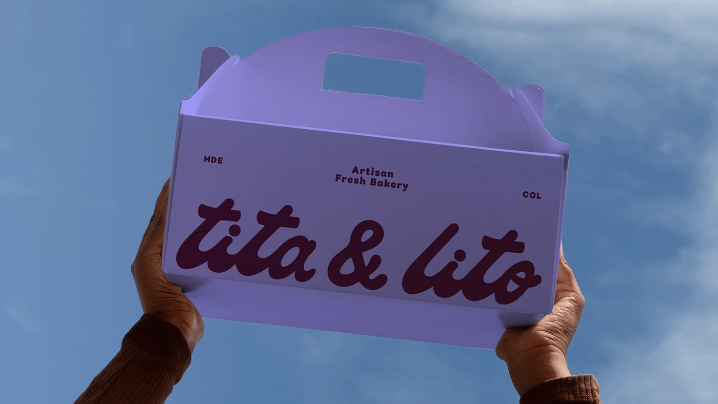 Hands holding a lavender bakery box with bold “tita & lito” logo lettering against a blue sky, showcasing clean modern typography and nostalgic brand identity design.