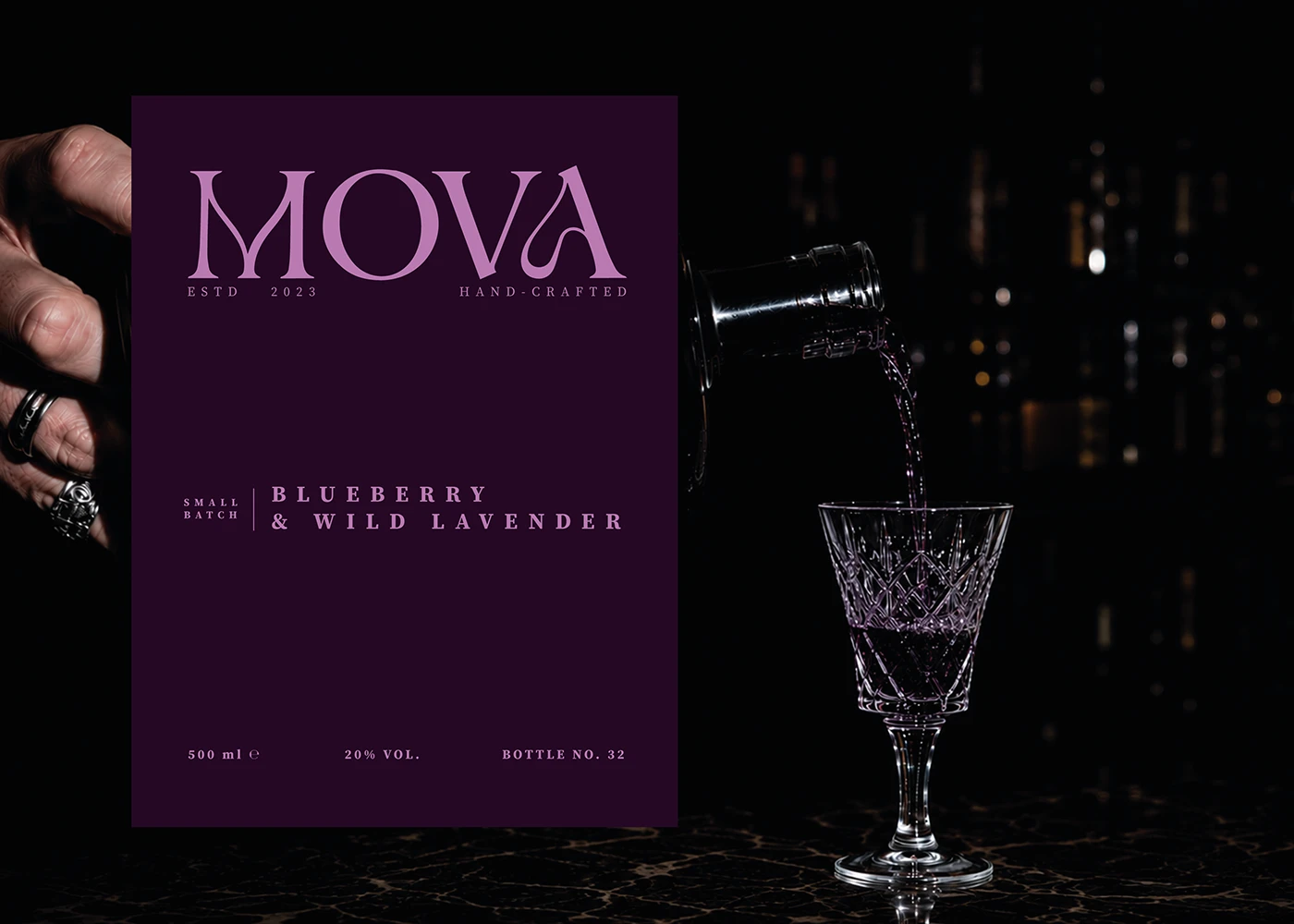 MOVA blueberry and wild lavender liqueur label beside a bottle pouring purple liqueur into a crystal glass.