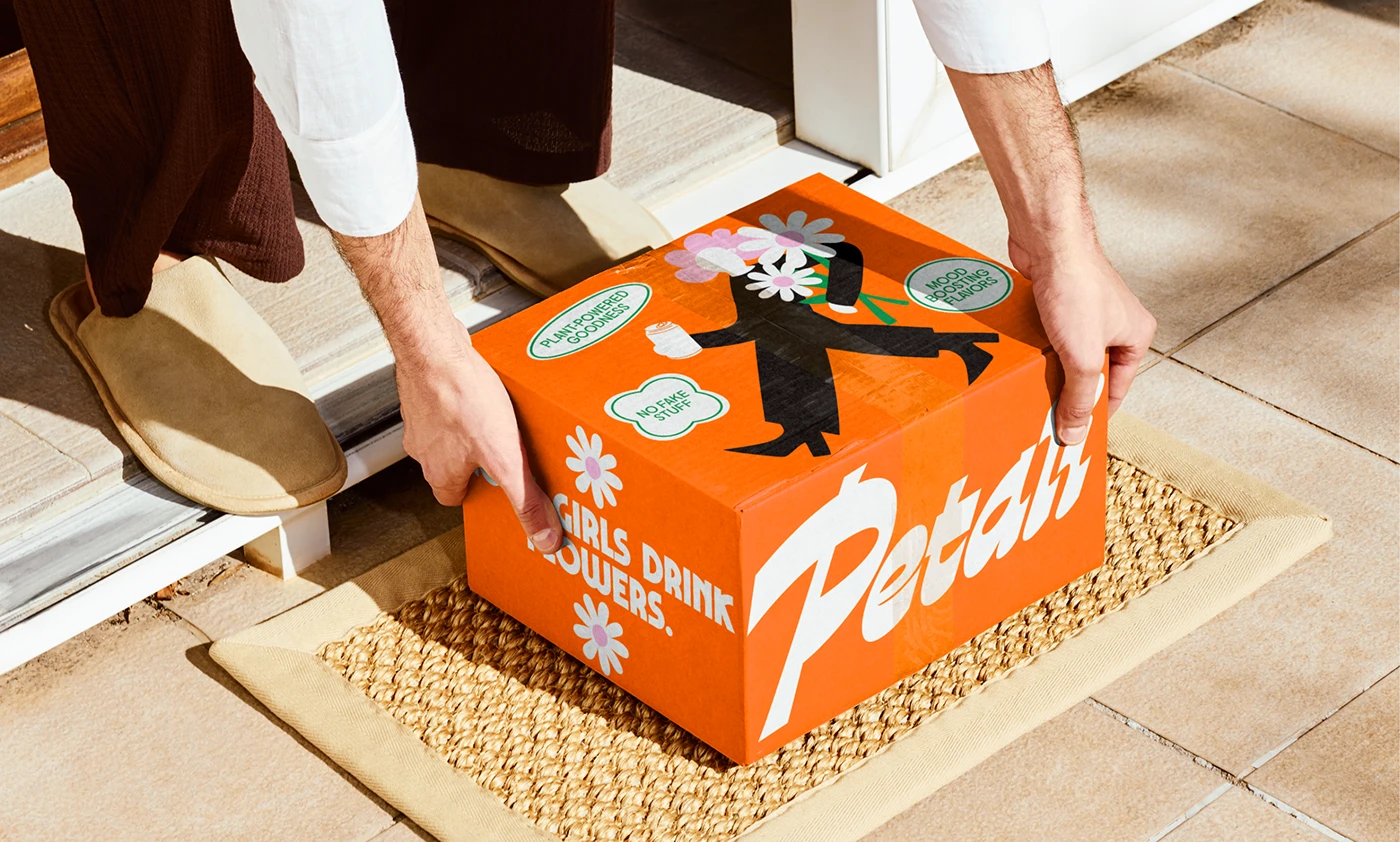 Petali Soda delivery box with playful floral illustrations and slogan “Cool Girls Drink Flowers” placed on a doorstep—retro beverage branding with dopamine color design.