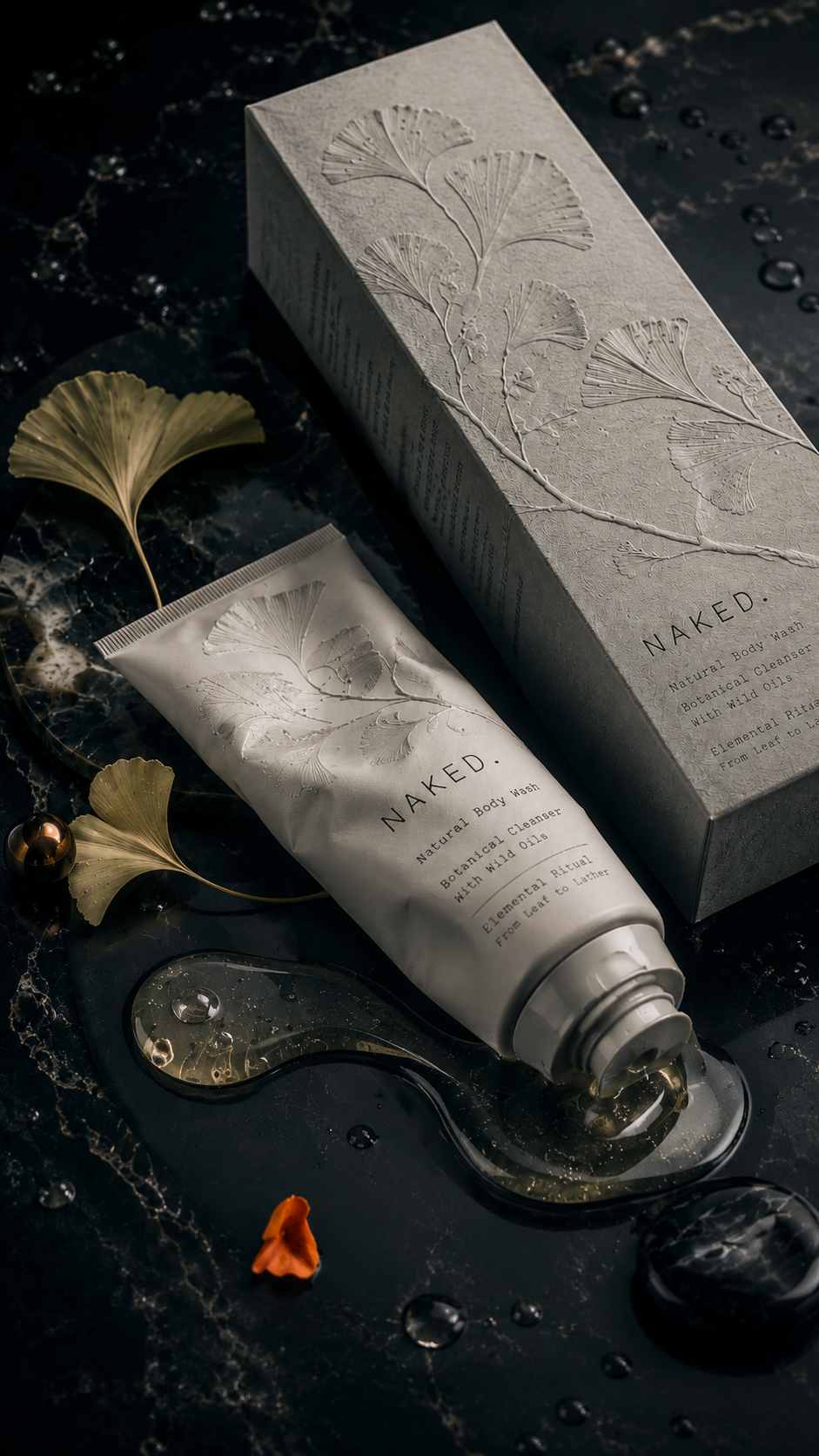 NAKED. body wash packaging with an embossed botanical tube and textured product box styled with ginkgo leaves, amber oil, water droplets, and dark stone.