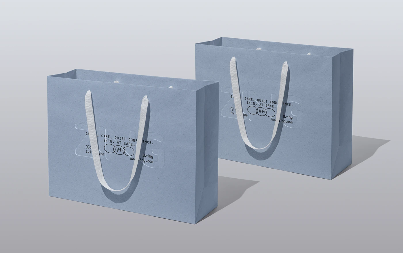 Two pale blue ZING branded shopping bags with white rope handles, featuring subtle embossed logo details and minimal black typography on a clean studio background.