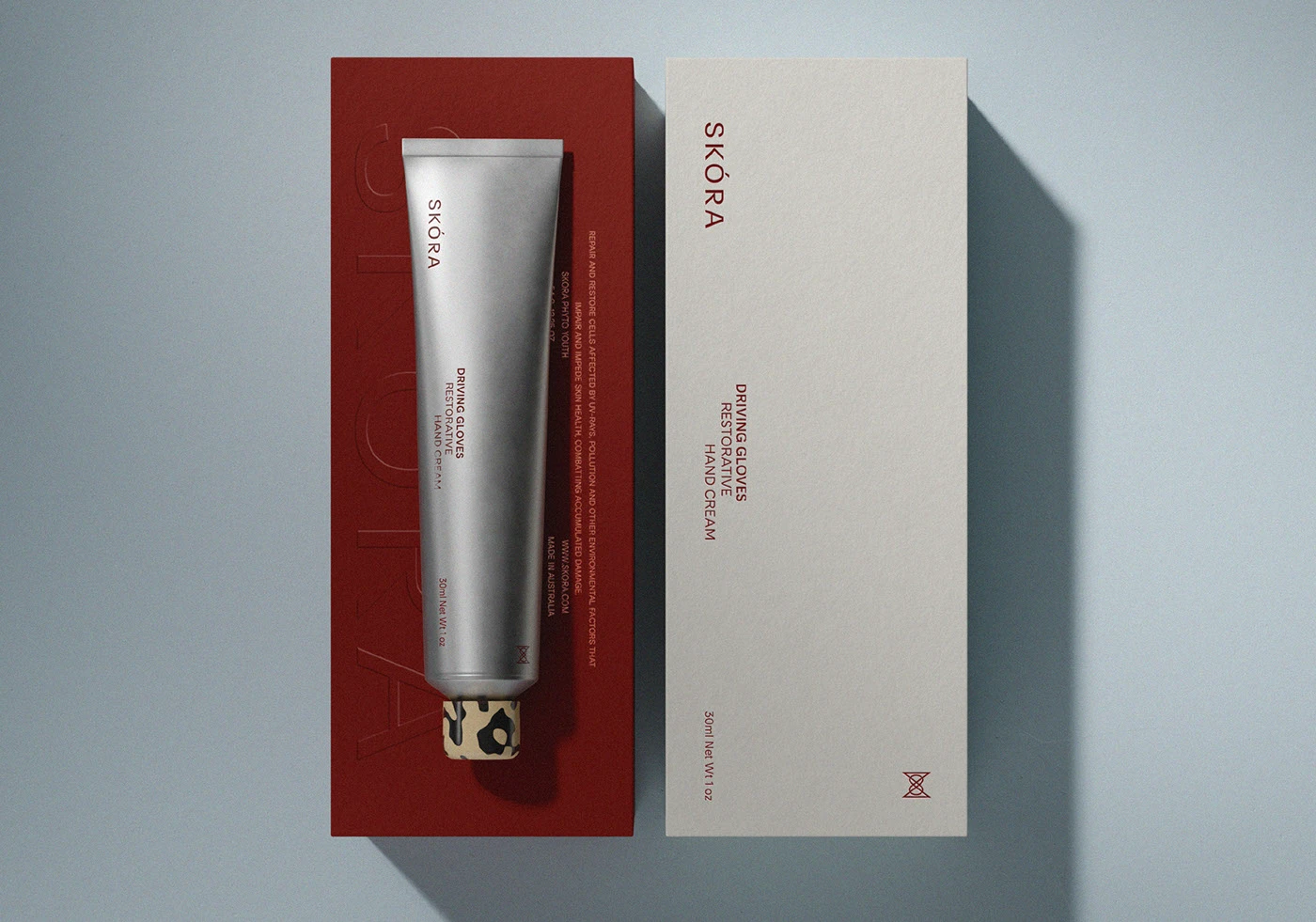 Skora Driving Gloves restorative hand cream packaging shown with aluminum tube and textured carton, highlighting typography-led design, astaxanthin-red detailing, and refined material contrast in premium bodycare packaging.