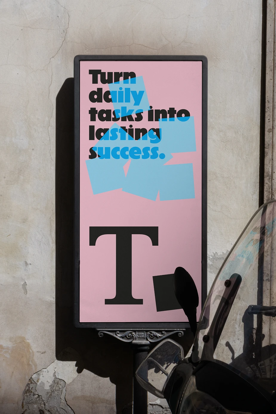 A pink and blue Taskly poster displayed on a weathered concrete wall, featuring bold typography reading “Turn daily tasks into lasting success,” with layered sticky-note graphics that highlight the brand’s playful, color-blocked identity.