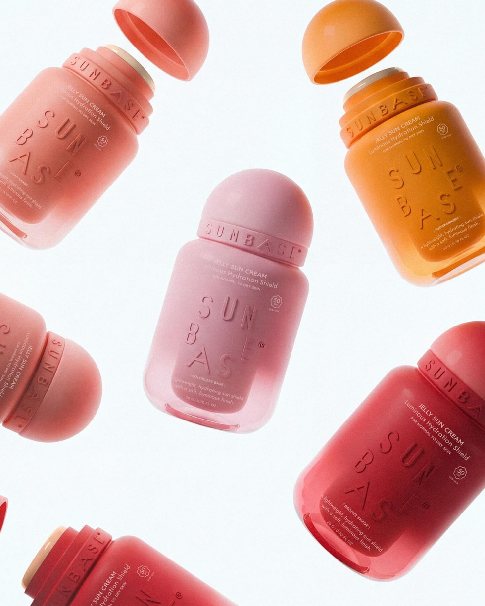 Sunbase sunscreen bottles in coral and orange tones floating on white background, modern skincare packaging design and brand identity