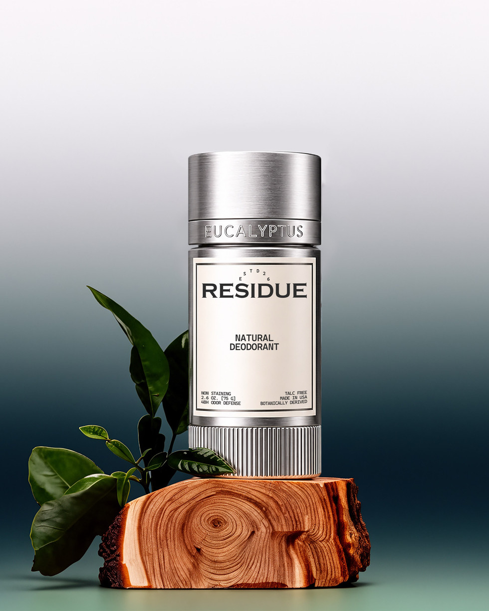 Silver eucalyptus natural deodorant stick displayed on a cut wood block with green leaves against a dark teal gradient background.