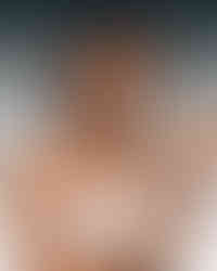 Person applying a silver natural deodorant stick with a powder blue label while wearing a white tank top against a soft gray gradient background.