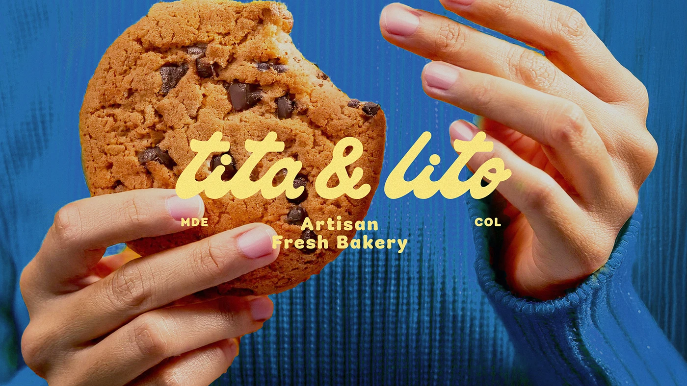 Hands holding a chocolate chip cookie with the Tita & Lito Bakery logo in soft yellow text, showcasing playful retro typography and warm artisan branding against a bold blue background.
