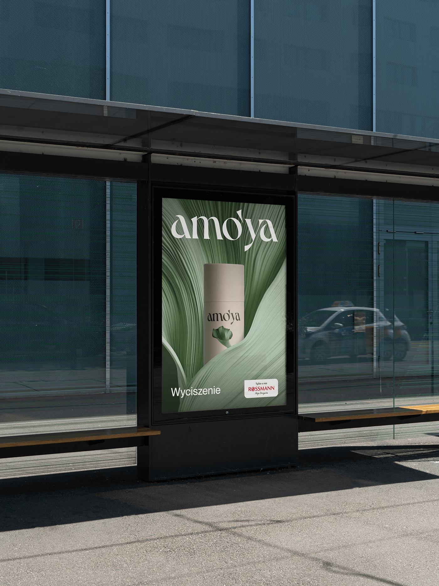 Amo’ya self-care advertisement displayed at a modern bus shelter, featuring cream product packaging surrounded by layered green botanical forms.
