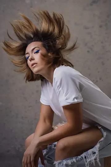 woman sitting wearing ripped jeans white tee and hair flipped up