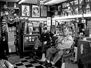 Two men in a vintage barbershop with memorabilia.
