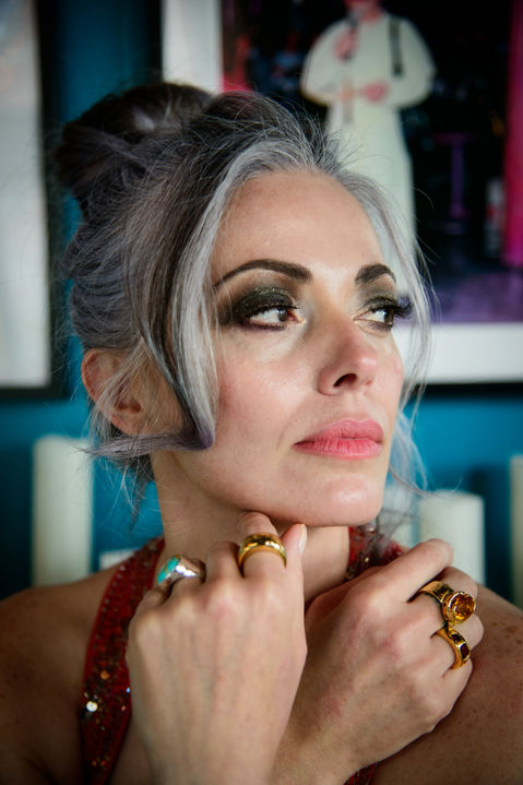 close up of woman with grey hair updo, hand under face with stacked lelamooi rings