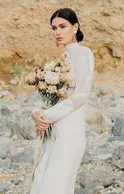 Bride in wedding dress holding bouquet of flowers outdoors