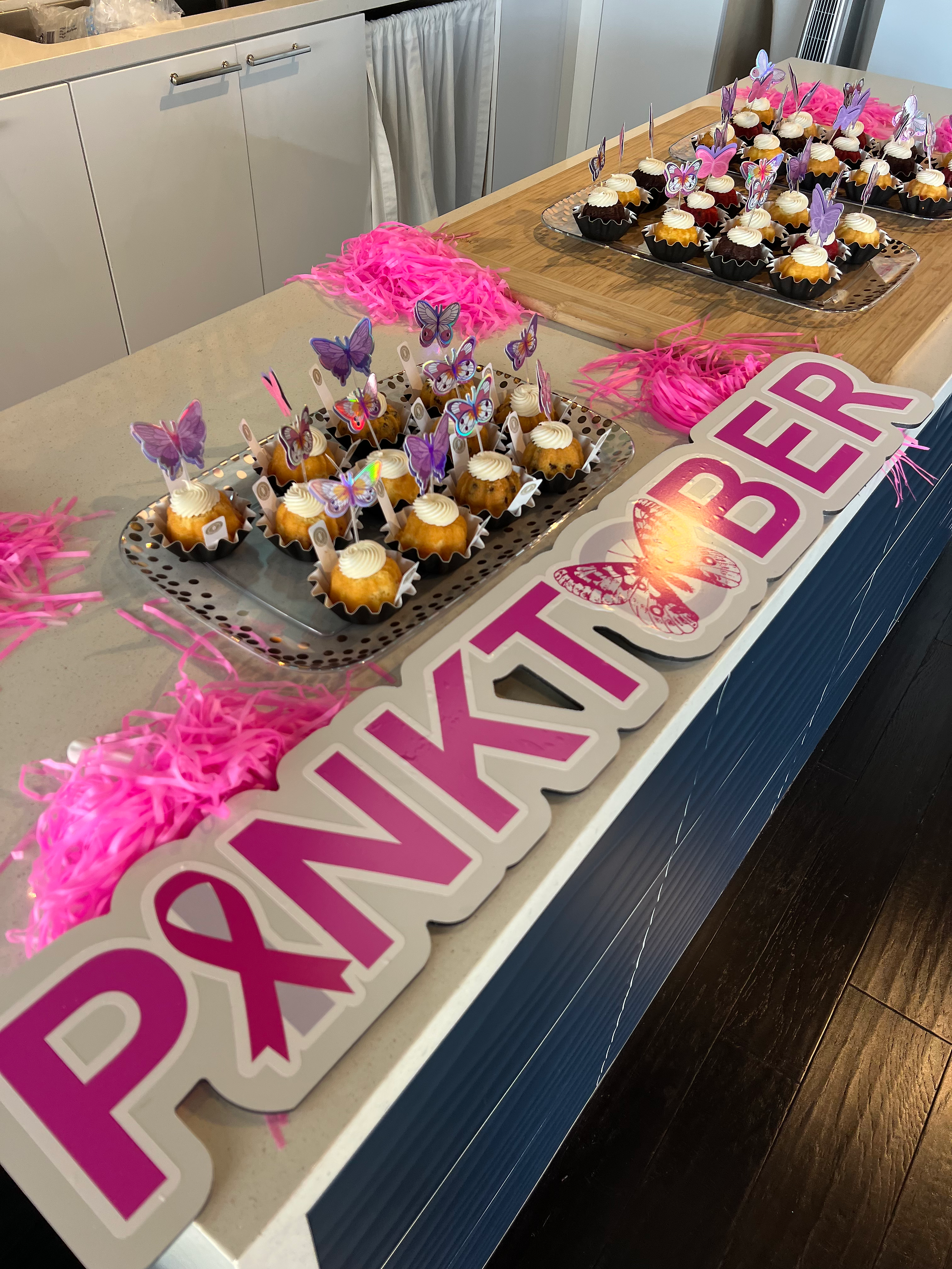 Cupcakes with butterfly toppers and Pinktober sign at the fundraiser.