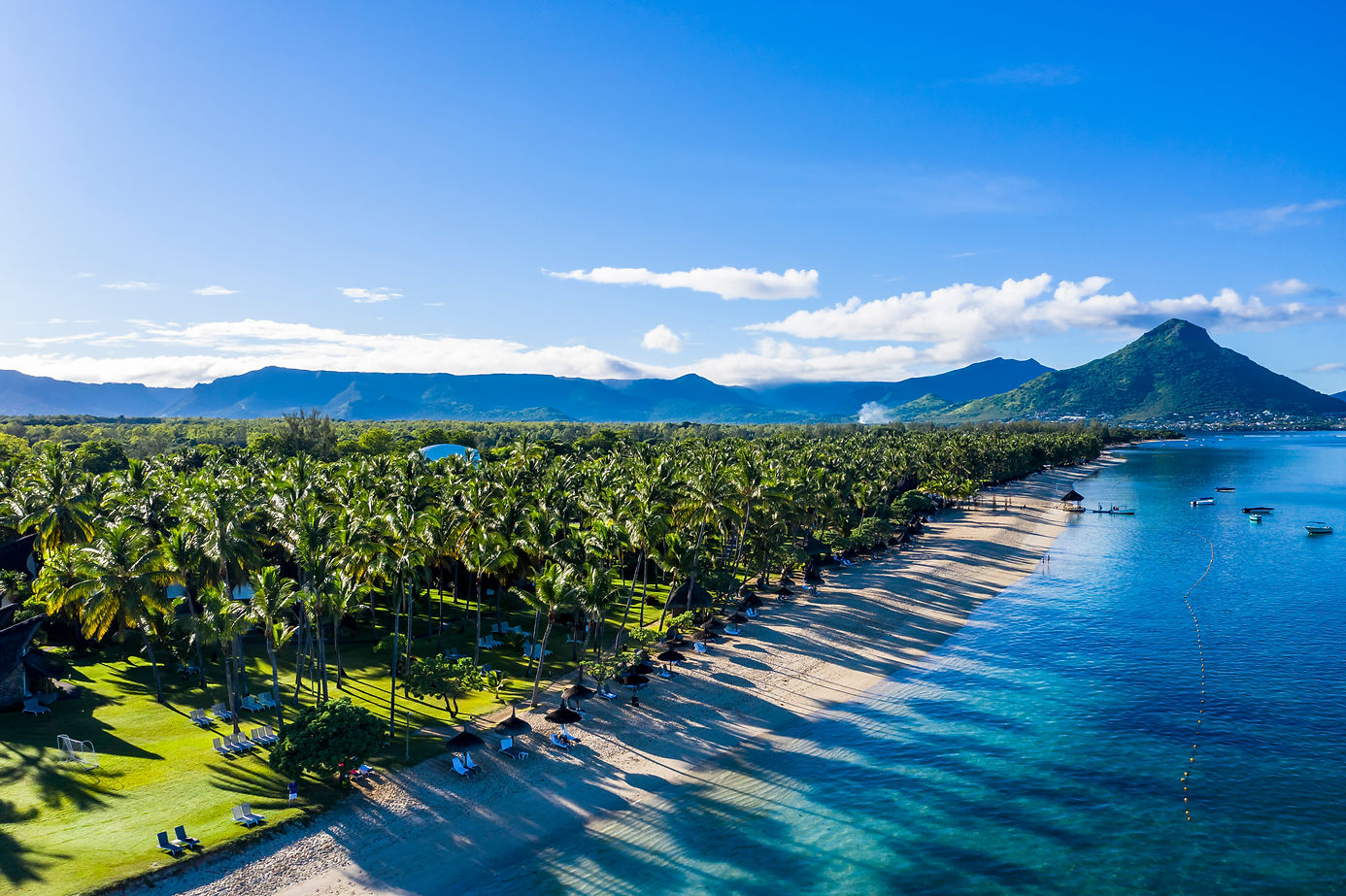 The beach at Flic en Flac with luxury hotels and palm trees, behind the mountain Tourelle 