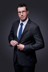 A headshot of a man in a suit and glasses. By Jeff B Photography