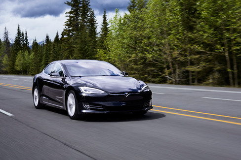 A Tesla Model S races down the highway outside of Banff, Alberta, by Jeff B Photography