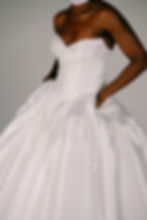 Woman in white strapless gown with structured bodice and full ruffled skirt.