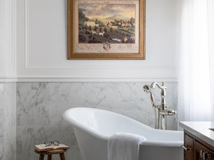 White marble bathroom with paneling and clawfoot tub