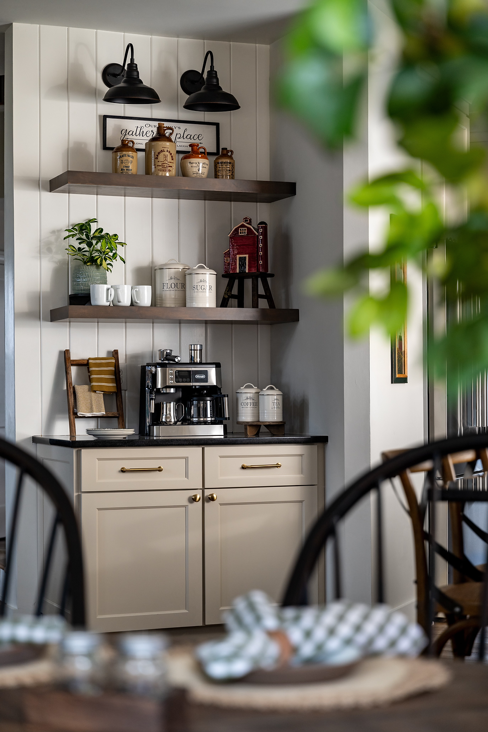 A breakfast bar with black countertops, floating shelves, and shiplap.