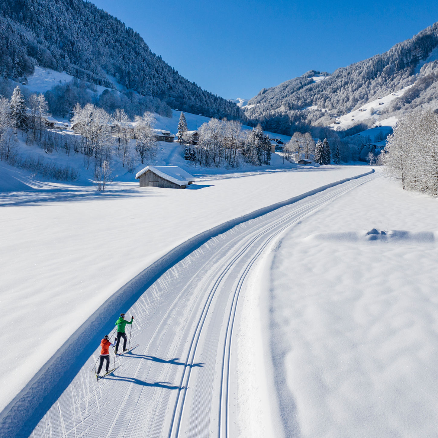 Zwei Skifahrer auf verschneiter Loipe, Berge und sonniges Winterlandschaft. Aktivitäten.