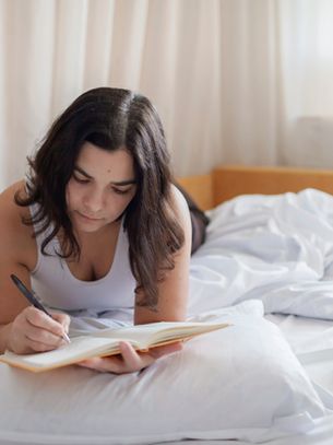 Woman sitting in bed with an open journal and coffee, reflecting on setting boundaries and self-care.