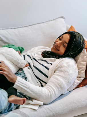 Tired mom practicing micro-rest for busy moms while resting on the couch with her child.