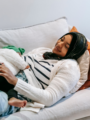 Tired mom practicing micro-rest for busy moms while resting on the couch with her child.